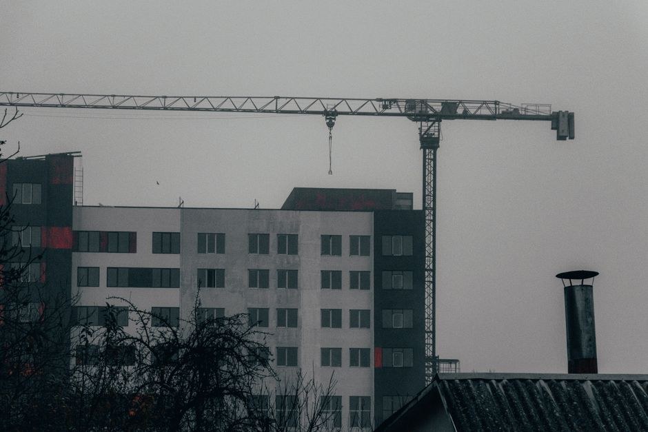 Arkistokuva: Keskeneräinen kerrostalo, jossa on tummia ja vaaleita julkisivuosia sekä punaisia yksityiskohtia, ja sen vieressä on korkea torninosturi.