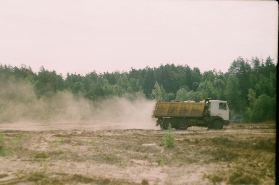 Arkistokuva: Valkoinen kippiauto keltaisella lavalla ajaa pölyisellä, kaivetulla alueella, taustalla näkyy metsää.