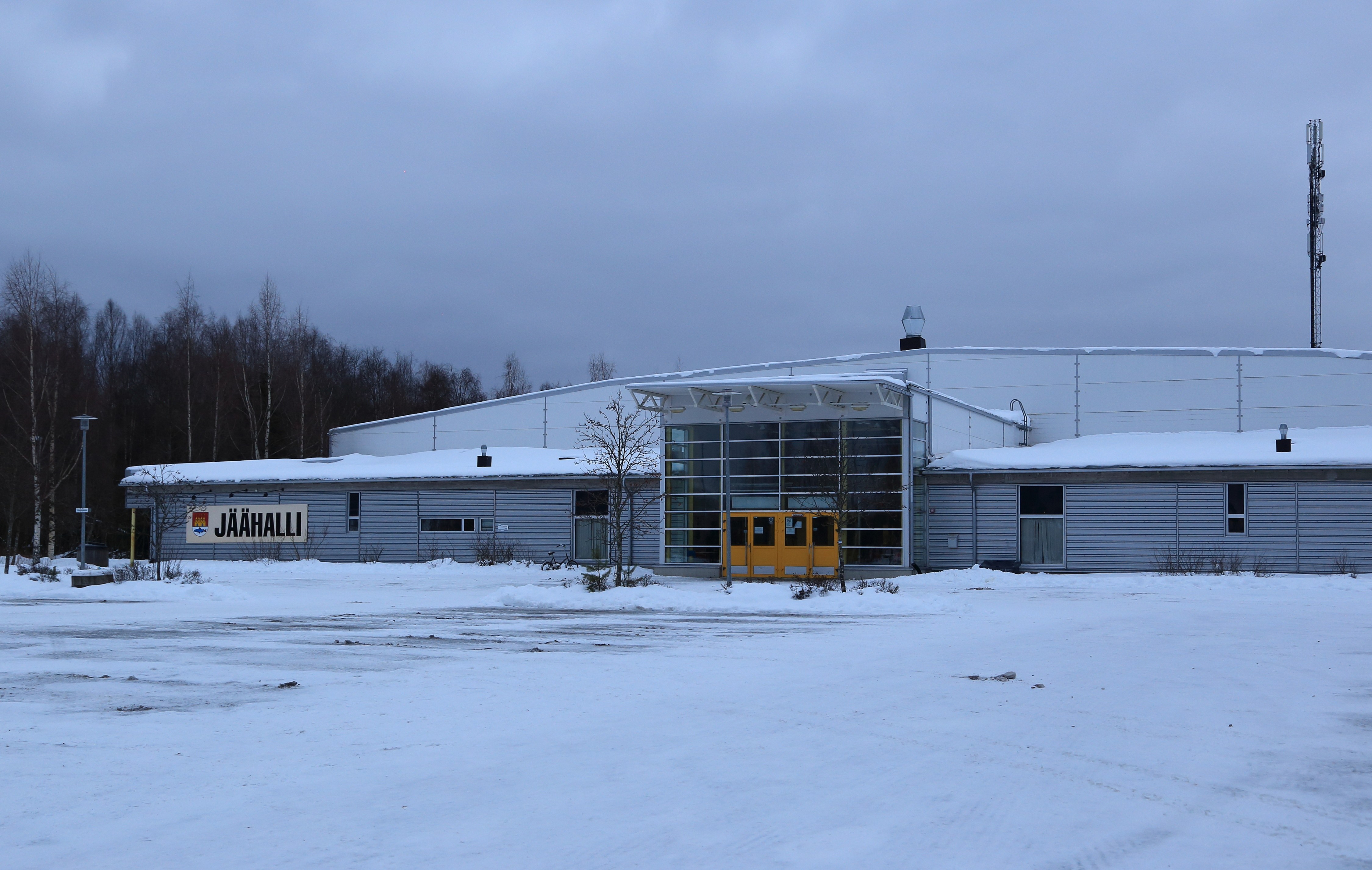 Arkistokuva: Linnanmaan jäähallin ulkonäkymä talvella, jossa etualalla on lumipeitteinen pysäköintialue ja taustalla puita.
