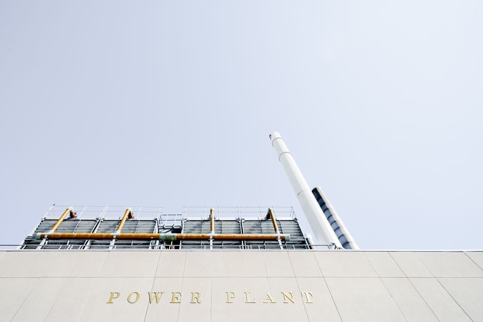 Arkistokuva: Voimalaitoksen julkisivussa on kultaiset kirjaimet "POWER PLANT", ja sen yläpuolella näkyy teollisuusputkia ja kaksi korkeaa valkoista savupiippua.