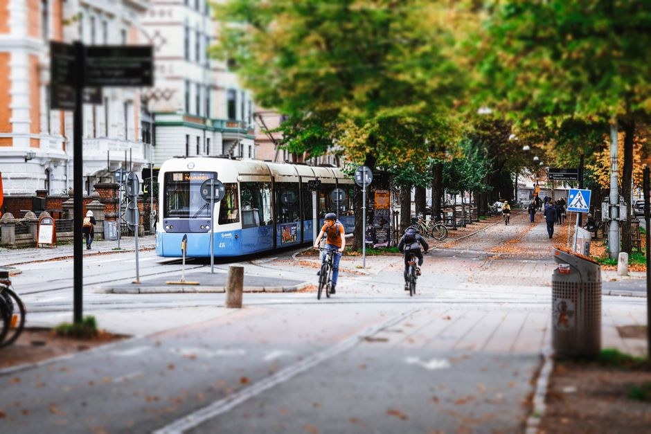 Arkistokuva: Kaksi pyöräilijää ajaa päällystetyllä tiellä raitiovaunulinjan ja puiden reunustaman kaupunkikadun vieressä syksyllä.