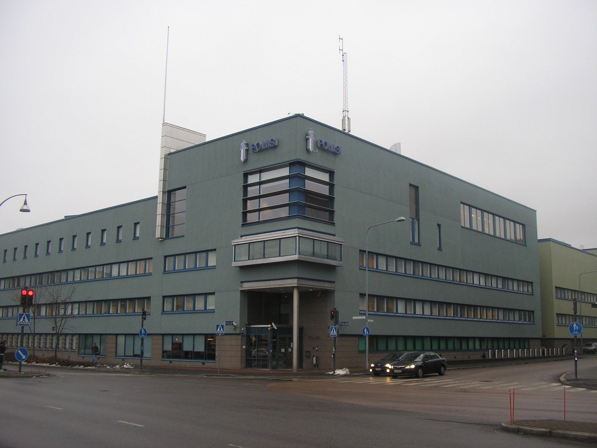 Arkistokuva: Suuri harmaanvihreä rakennus, jossa on useita ikkunoita ja sisäänkäynti, näkyy kadunkulmasta. Julkisivussa lukee sinisin kirjaimin "POLIISI".