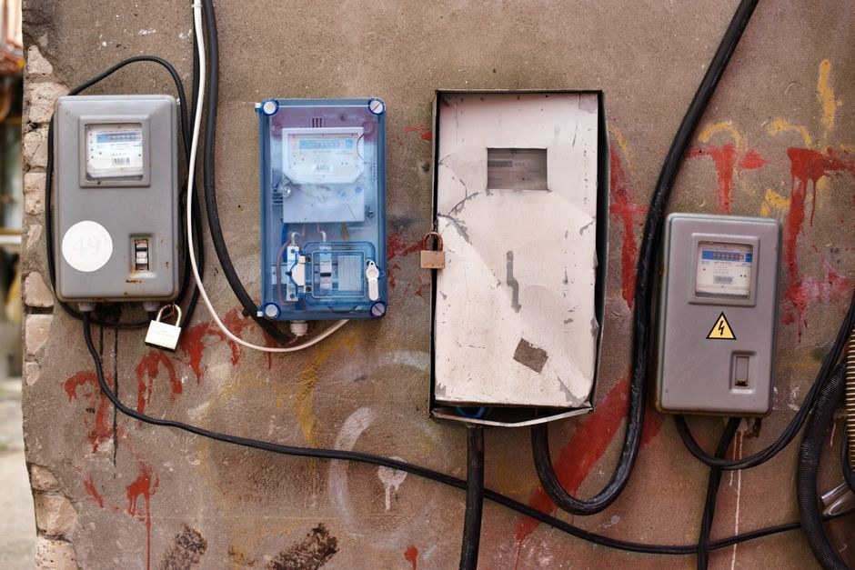 Arkistokuva: Neljä sähkömittaria ja sähkökaappia on asennettu graffitein peittämälle betoniseinälle, ja niitä yhdistävät mustat johdot.
