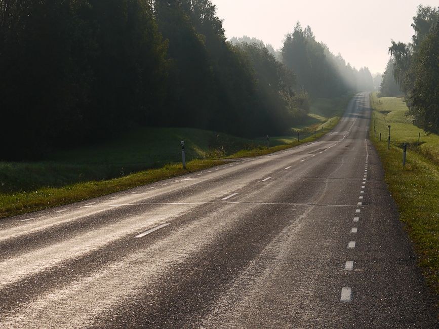 Arkistokuva: Kapea asfalttitie kulkee metsän ja pellon välissä, ja sen pinnassa näkyy halkeamia ja kuluneita merkintöjä.